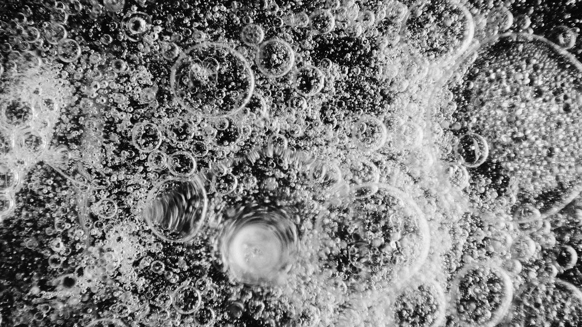 Macro black and white close-up of clustered bubbles and foam with varying ring sizes.